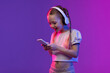 Pretty preteen blonde girl using smartphone and headphones, copy space