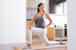 Young latin woman stretching hip flexor muscles on a yoga mat in her living room.