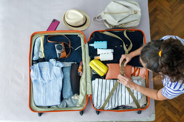 Top view of young woman packing suitcase for travel