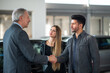 © Minerva Studio - Car dealer giving handshake to a young couple