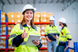 © narong - Warehouse worker young woman hold tablet with show thumbs up and look at camera and smiling with her coworkers discuss in the background.