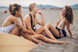 © Zamrznuti tonovi - Portrait of a three attractive woman friends sitting on a sandy beach