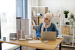 © sofiko14 - Arabian businesswoman in hijab scanning building models of city complex while comparing data on laptop in architecture office. Design professional devising engineering plan using advanced technology.