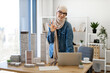 © sofiko14 - Adult arabian female in hijab posing behind writing desk with gadgets and maquettes in architecture office. Experienced professional having coffee break from project management in creative workplace.