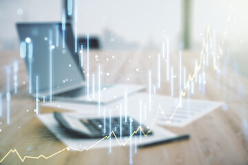 Double exposure of abstract creative financial chart hologram on blurry calculator with laptop background, research and strategy concept