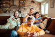 © Baba Images - Young family playing video games together in the living room on a gaming console