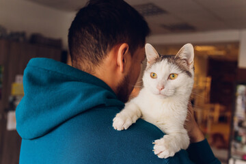 young man holding a white cat close-up.