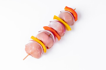 Wall Mural - Skewers with pieces of raw meat, red, yellow and green pepper.Top view.Raw chicken leg meat skewers with vegetables, peppers, onions, on a white background.Uncooked mixed meat skewer with peppers.