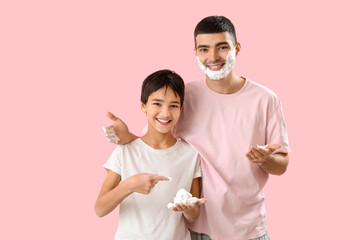 Poster - Man and his little son applying shaving foam onto faces against pink background