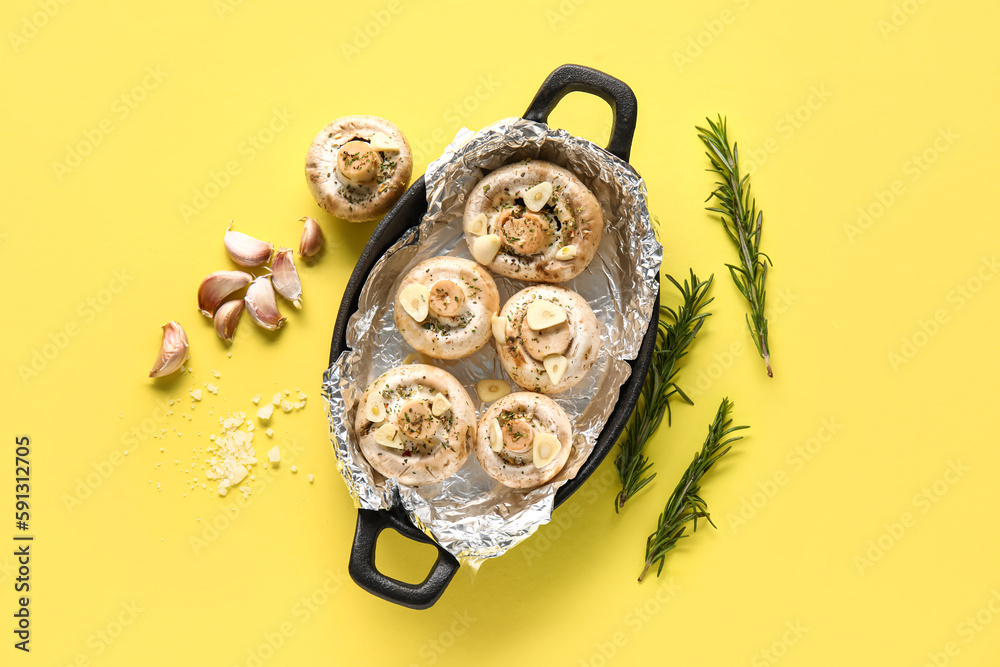 Baking dish with raw mushrooms, spices and rosemary on yellow background