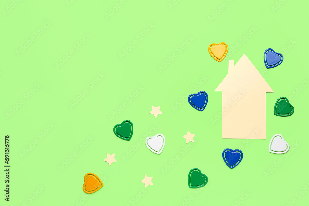 Paper house with hearts and stars on green background. Children's Day celebration