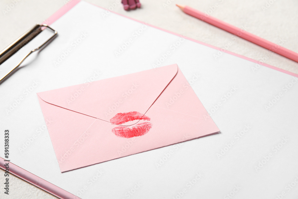 Envelope with lipstick kiss mark and clipboard on white background, closeup