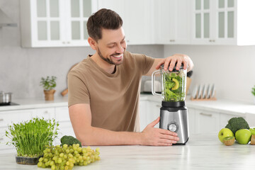 Poster - Happy man blending delicious smoothie at white marble table in kitchen