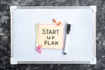 Wall Mural - top view start up plan note on sticker inside open copybook on a gray background school lesson stude