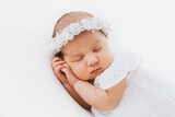 Fototapeta  - Newborn baby girl portrait, photographed in studio. Dressed in white dress.