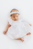 Fototapeta  - Newborn baby girl portrait, photographed in studio. Dressed in white dress.