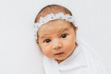 Fototapeta  - Newborn baby girl with opened eyes, looking at the camera.