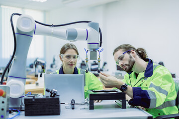 Female engineers checking or maintenance electronic in AI Robot, robot arm in the manufacturing automation and robotics manufacture room.