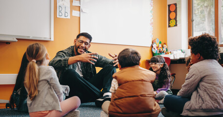 Male educator talking to his students in a classroom. Man teaching elementary school children