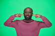 © pressmaster - Portrait of African American man looking at camera and covering his ears to ignore isolated on green background