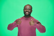 © pressmaster - Portrait of happy African American man showing thumbs up and smiling at camera standing on green background