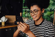 © Drobot Dean - Smiling african woman using smartphone while sitting in kitchen