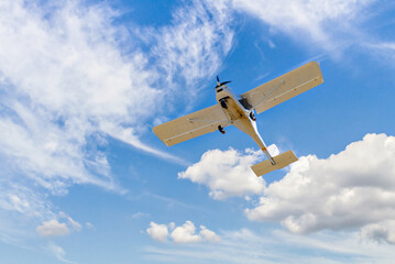 Wall Mural - Single engine ultralight plane flying in the blue sky with white clouds