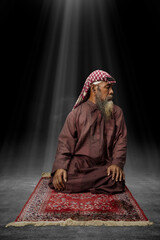 Poster - Muslim man with a beard wearing keffiyeh with agal in praying position (salat) on the prayer rug