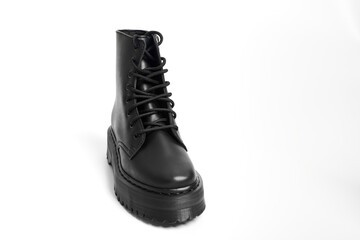 One black women combat boot on high heel platform with lug sole on isolated white background. Military stylish high heel platform combat shoe for woman leg, new footwear trend