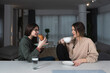 © Srdjan - Two millennial girl friends at home talking, drinking coffee, discussing. Diverse friends spending fun time together and laughing, chat and talk. Neighbors having fun at free time