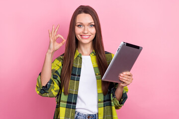 Poster - Portrait of satisfied friendly girl with straight hairdo dressed plaid shirt hold tablet showing okey isolated on pink color background