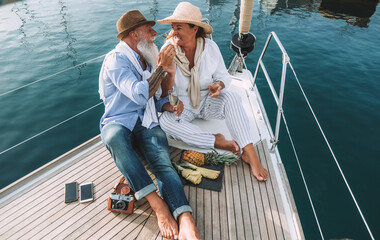 Wall Mural - Senior couple drinking champagne on sailboat during summer vacation - Soft focus on woman hat