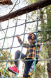 © Tetiana Soares - Toddler boy climbs up a high alpine grid on wooden playground in public adventure park. Children outdoor equipment for entertaining and recreation, healthy lifestyle and muscle development