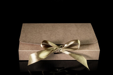 Man gift concept. gift box wrapped in craft paper with luxury bow on dark background. Horizontal with copy space.