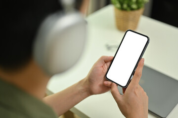 Close up view of man wearing wireless headphone using mobile phone. Blank screen for advertising text message