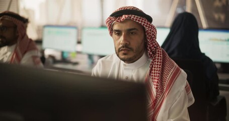 Leinwandbilder - Portrait of a Middle Eastern Engineer Working on Desktop Computer in a Fintech Startup Company. Arab Software Developer Researching New Ideas to Problem Solve a Technical Assignment. Warm Color Edit