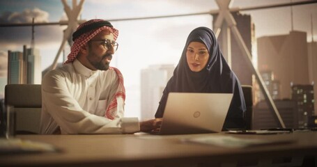 Poster - Two Diverse Muslim Financial Advisers Use Laptop Computer to Discuss a Stock Market Strategy in a Modern Industrial Office. Female and Male Arab Managers Work in a Banking Development Center