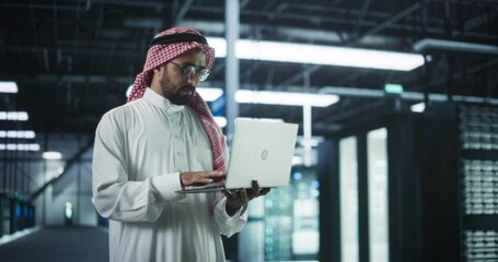 Poster - Muslim Data Center IT Engineer Standing in a Room with Operational Server Racks. Cloud Computing Architect Uses Laptop Computer for Servicing the System in Cyber Security and Data Protection Facility