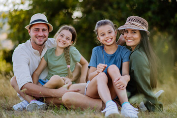 Wall Mural - Happy family sitting on a medow, resting after hiking in nature.