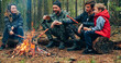 © Valua Vitaly - Family sits around a campfire on a summer evening. Children with parents are resting in the woods. Family frying sausages over a fire in the woods. Weekend in nature in good company.