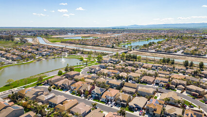 Wall Mural - Drone photos over The Lakes community in Discovery Bay, California with houses, houses with solar, a lake with fountains, roadways and a beautiful blue sky with room for text