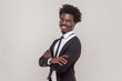 © khosrork - Portrait of cheerful man with Afro hairstyle with crossed arms, smiling broadly, laughing at good joke, wearing white shirt and tuxedo. Indoor studio shot isolated on gray background.