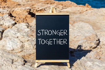 Wall Mural - Stronger together symbol. Concept words Stronger together on black chalk blackboard on a beautiful stone background. Business, motivational and stronger together concept.