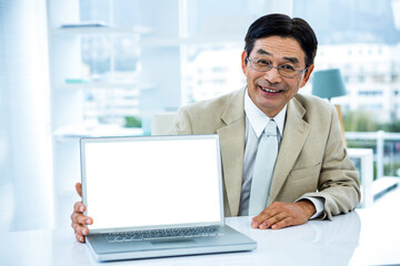 Poster - smiling asian businessman showing his laptop