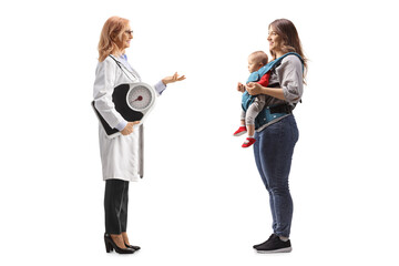 Poster - Full length profile shot of a  female doctor holding a weight scale and talking to a mother with a baby