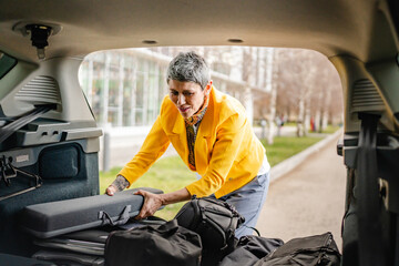 one senior woman pack luggage baggage suitcase in the trunk of the car