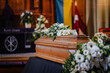 A coffin decorated with many flowers and candles in a beautiful church, ceremony