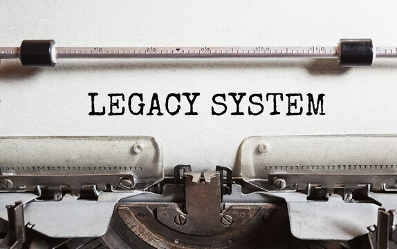The text LEGACY SYSTEM is typed on paper by an antique typewriter. Vintage inscription, retro style, grunge, concept.