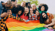 © Vane Nunes - Happy diverse people holding lgbt rainbow flag outdoors - Diversity concept - Soft focus on Asian woman young woman face