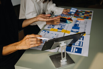 Close up ux developer and ui designer brainstorming about mobile app interface wireframe design on table with customer breif and color code at modern office.Creative digital development agency